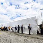 MTA and manufacturing company officials get ready to unveil the new train car, which is hidden under a huge sheet.
